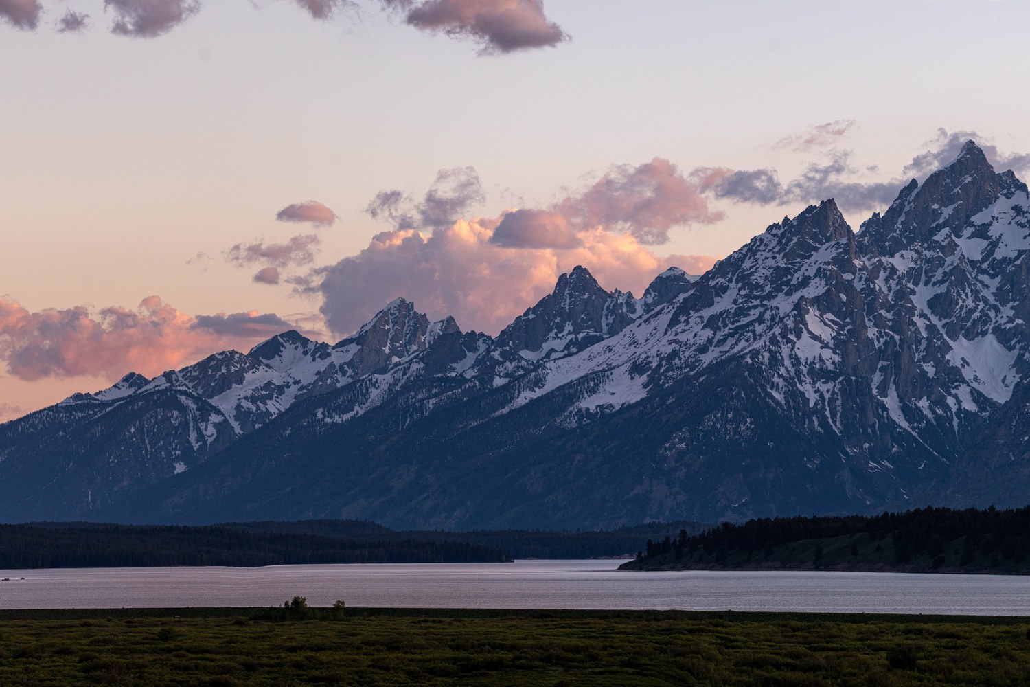 Jackson Lake still and grey below the Teton peaks at dusk.